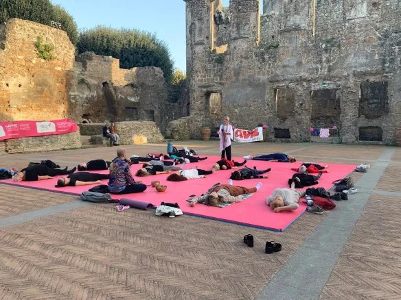 Pratica di yoga all'aperto dentro le mura del castello di Nepi, un gruppo disteso sui tappetini al tramonto